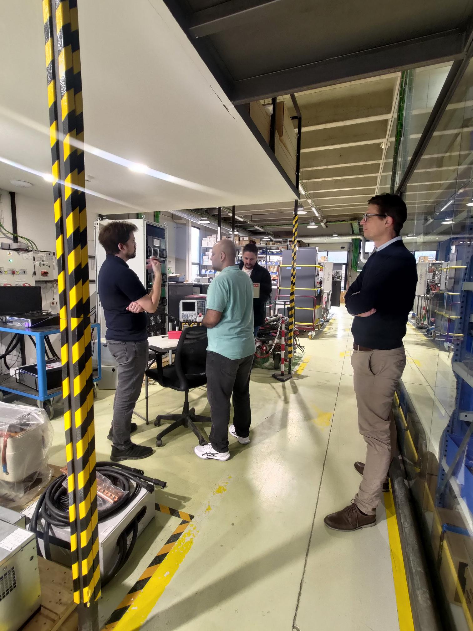 Cinergia and OPAL-RT teams reviewing a laboratory setup for advanced PHIL and real-time power testing.